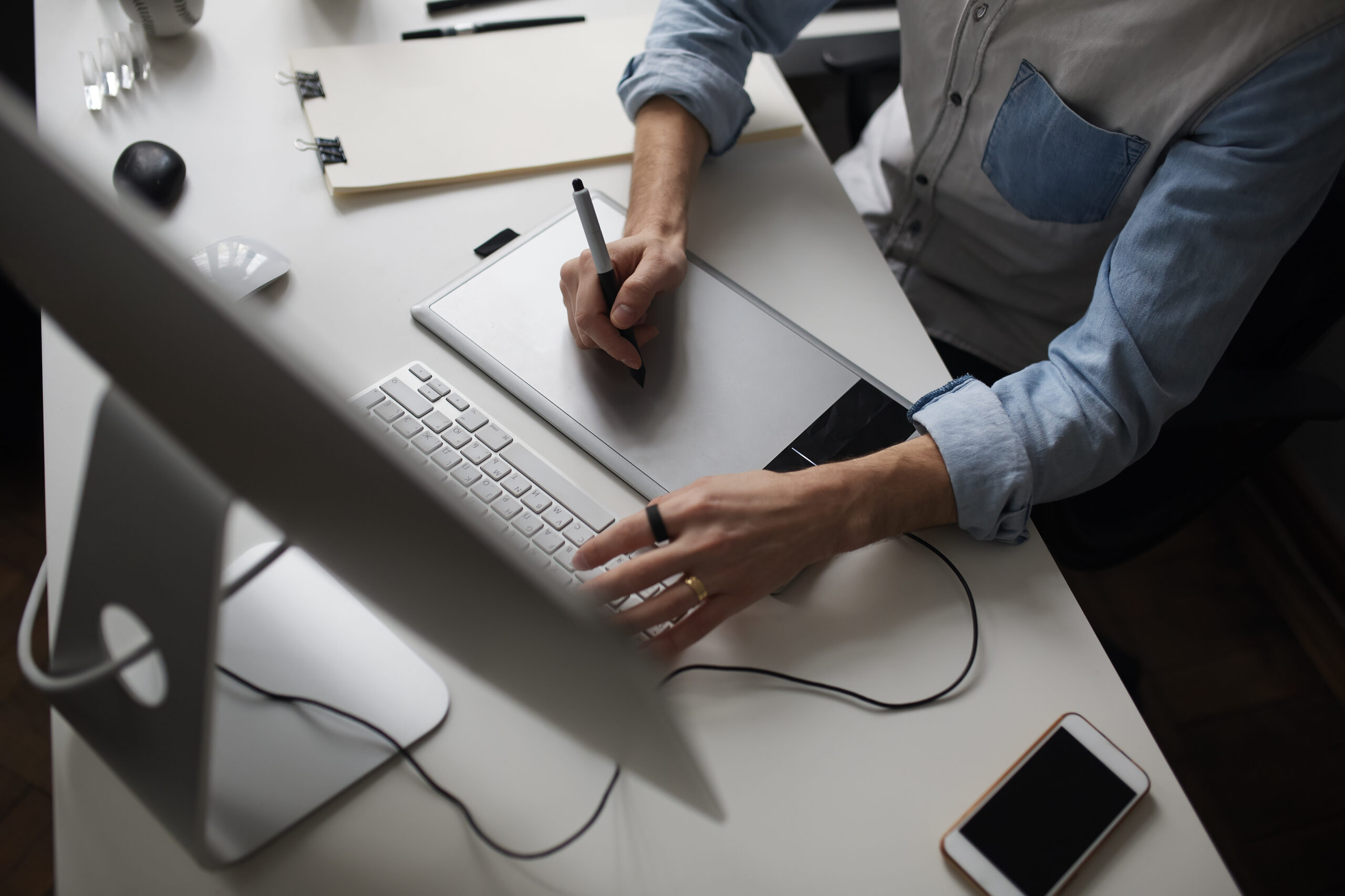 Designer hands using graphics tablet while working with computer at studio or office. Top side view.